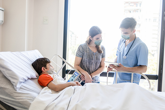 男孩躺在病床上,母亲与医生交谈