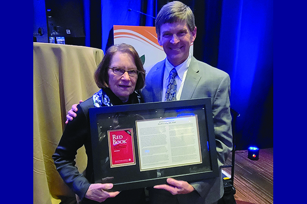 Red Book Editor David W. Kimberlin, M.D., FAAP, presents Sarah S. Long, M.D., FAAP, with a copy of a dedication in the 2024 Red Book