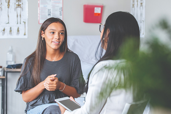 Teenager talks to her doctor.