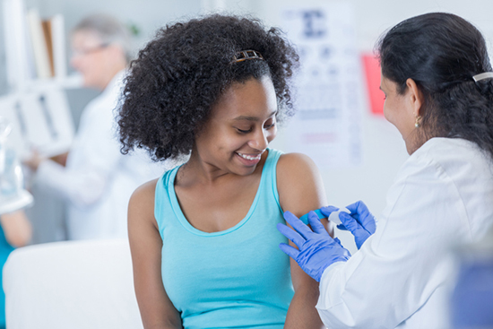 Teen girl getting vaccine in arm.