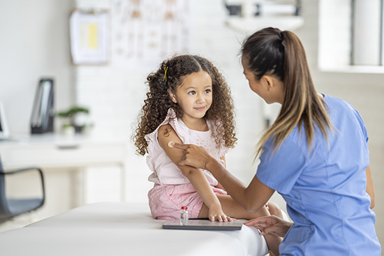 Girl with bandaid on arm after vaccine.