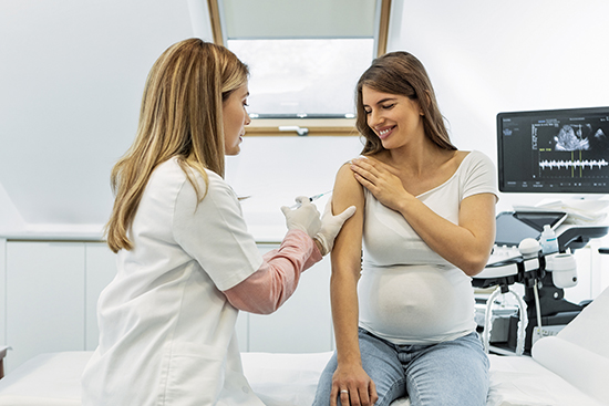 Pregnant woman getting a vaccine in her arm.